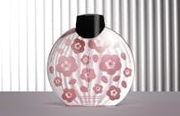 Elegant perfume bottle with cherry blossom design against a striped background.